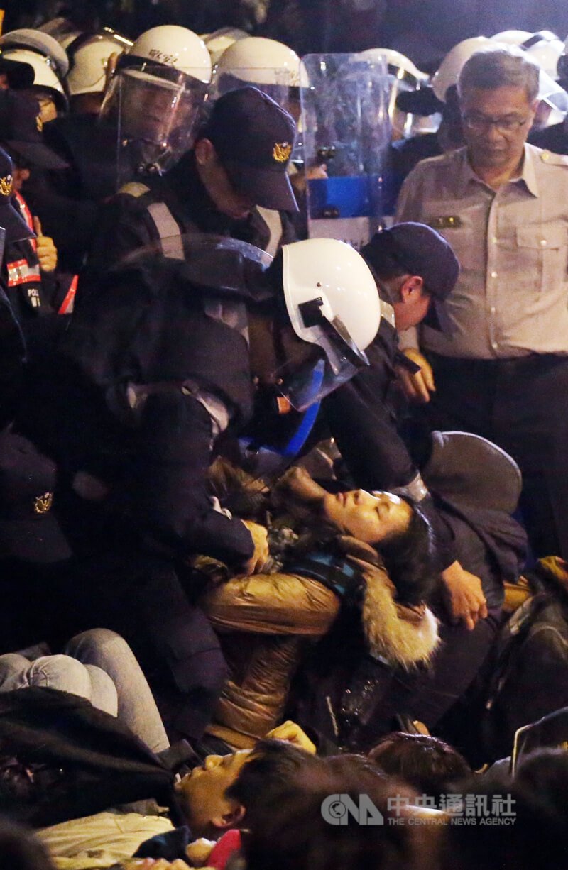 警方在行政院內徒手搬離抗議群眾,一名女子遭抬起。(中央社檔案照片)