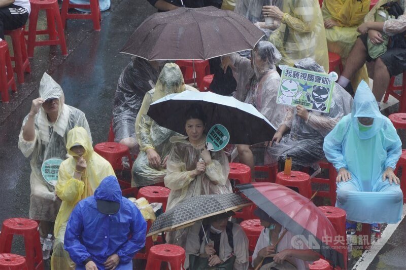 對流雲系發展旺盛，21日午後台北市下起傾盆大雨，於立法院外集結參與「青鳥行動」的民眾在雨中聆聽台上公民團體代表宣講。中央社記者徐肇昌攝 113年6月21日
